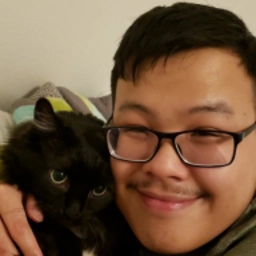 Picture of Quang and his mostly black munchkin cat Chickadee circa 2020